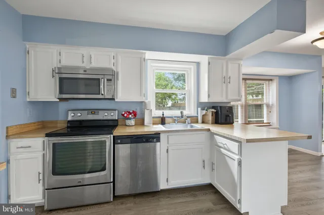 a kitchen with cabinets stainless steel appliances and a window