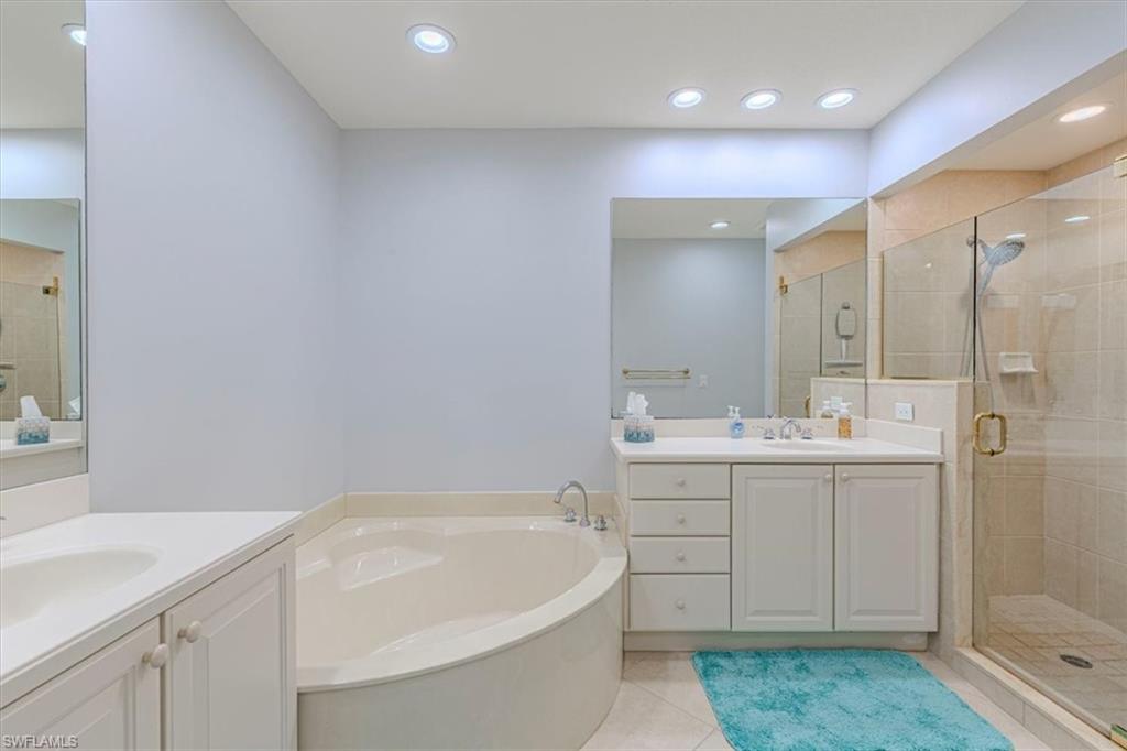 7837 Hawthorne Drive, Unit 1102 Naples, FL 34113 - Photo 15 of 33 Full bath with a stall shower, light tile patterned floors, a garden tub, two vanities, and recessed lighting