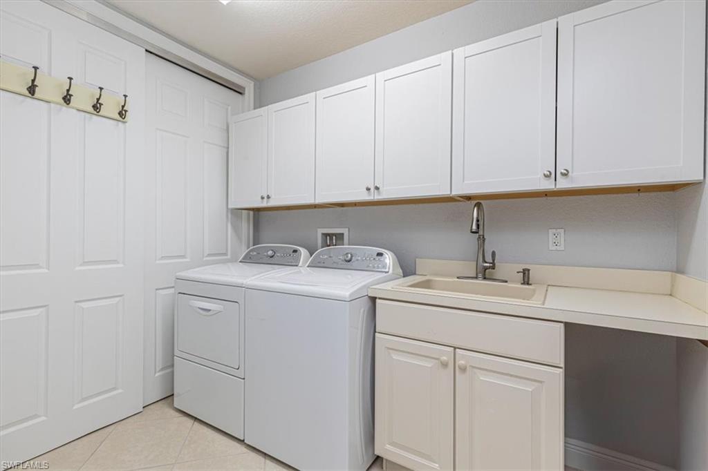 7837 Hawthorne Drive, Unit 1102 Naples, FL 34113 - Photo 22 of 33 Laundry room featuring light tile patterned floors, washing machine and clothes dryer, and cabinet space