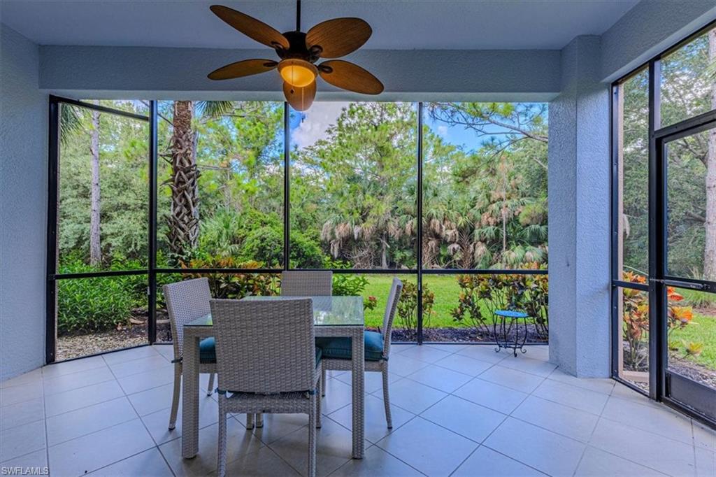 7837 Hawthorne Drive, Unit 1102 Naples, FL 34113 - Photo 3 of 33 Sunroom featuring outdoor dining area, a ceiling fan, and view of scattered trees