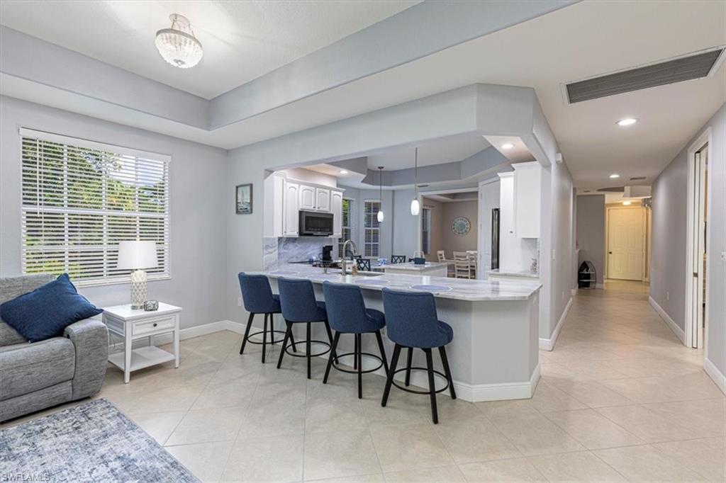 7837 Hawthorne Drive, Unit 1102 Naples, FL 34113 - Photo 7 of 33 Kitchen featuring white cabinetry, a kitchen bar, pendant lighting, light tile patterned flooring, and a peninsula