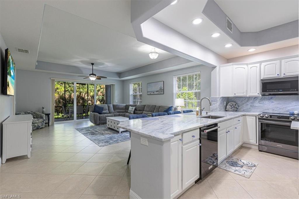 7837 Hawthorne Drive, Unit 1102 Naples, FL 34113 - Photo 33 of 33 Kitchen featuring a tray ceiling, appliances with stainless steel finishes, light tile patterned floors, open floor plan, and recessed lighting