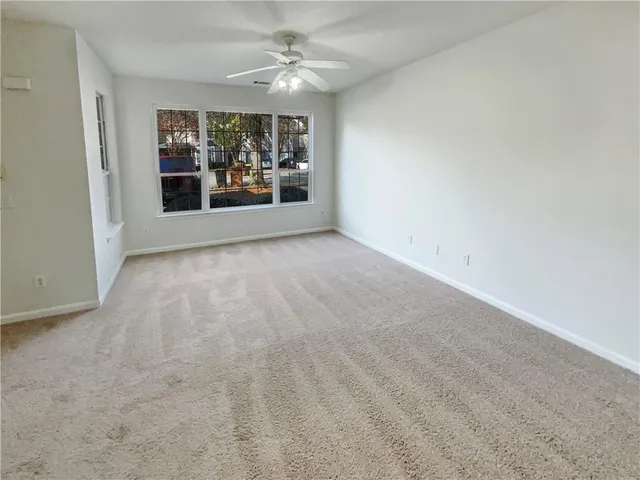 an empty room with windows and ceiling fan