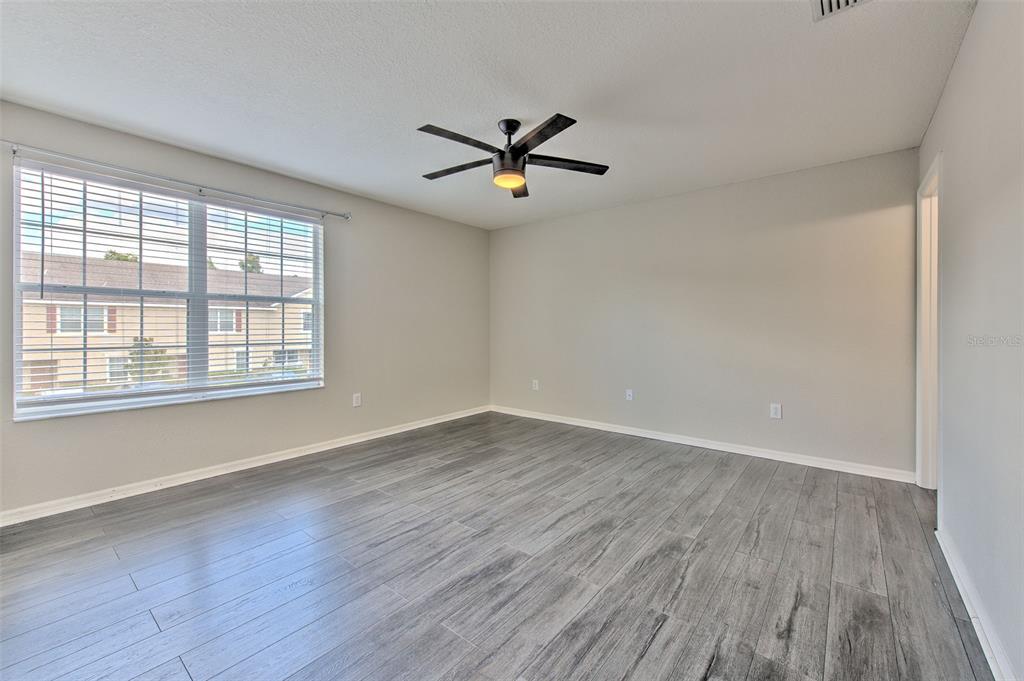 27528 Desert Willow Way Wesley Chapel, FL 33544 - Photo 12 of 24 an empty room with wooden floor fan and windows