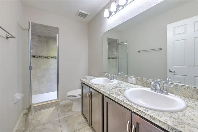 a bathroom with a granite countertop sink a toilet and shower