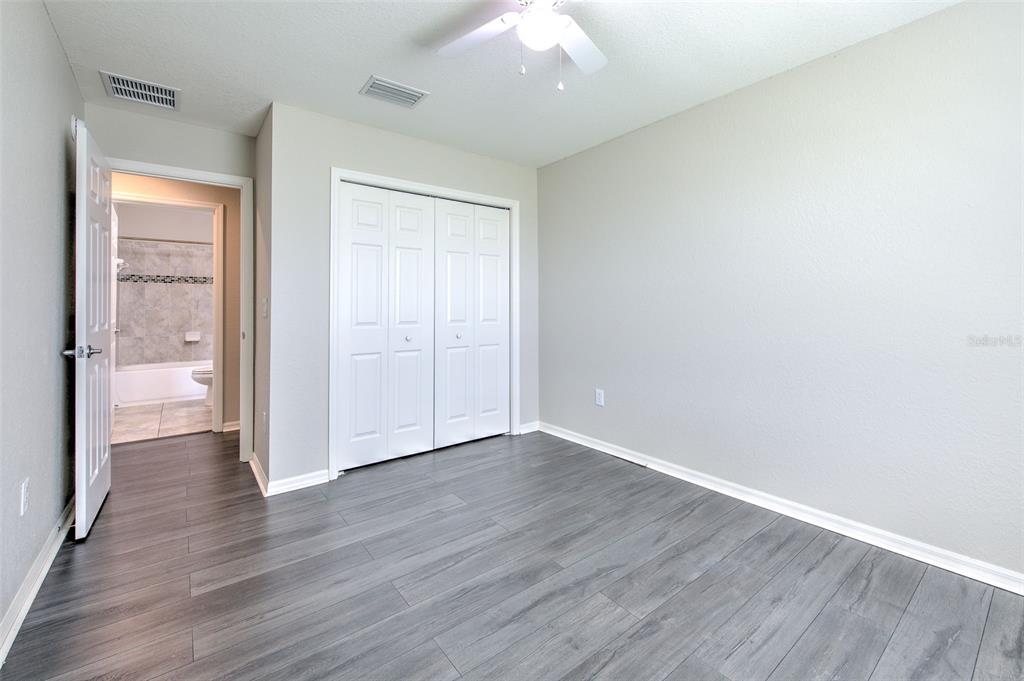 27528 Desert Willow Way Wesley Chapel, FL 33544 - Photo 18 of 24 an empty room with wooden floor and a bathroom