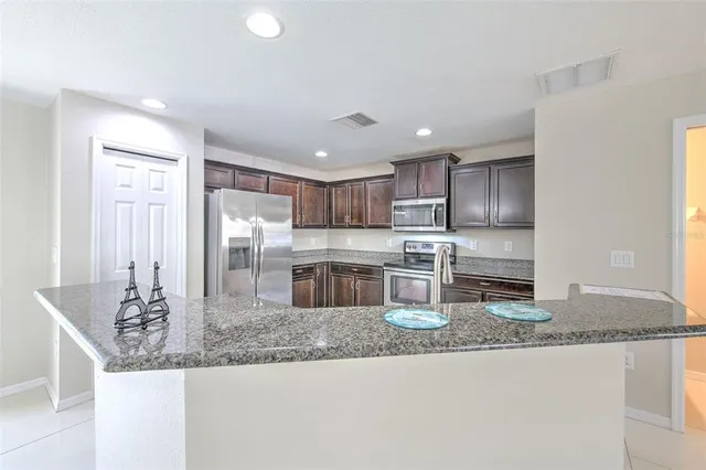 a kitchen with stainless steel appliances granite countertop a sink refrigerator and cabinets