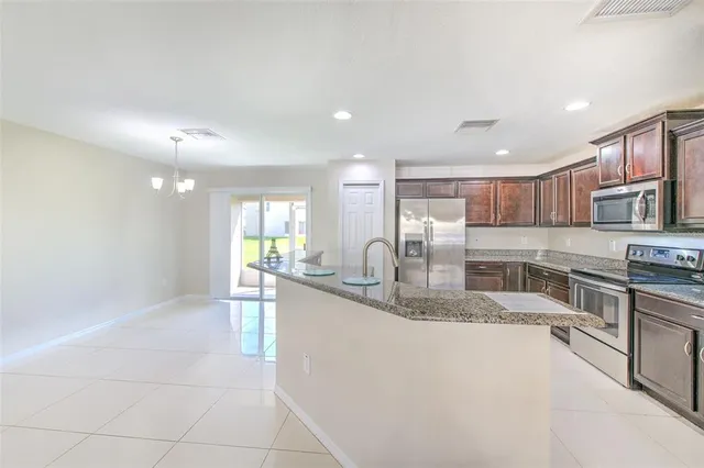 a large kitchen with granite countertop a large counter top stainless steel appliances and cabinets