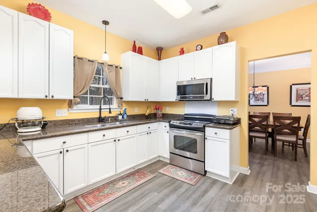 a kitchen with stainless steel appliances granite countertop a stove a sink and a microwave