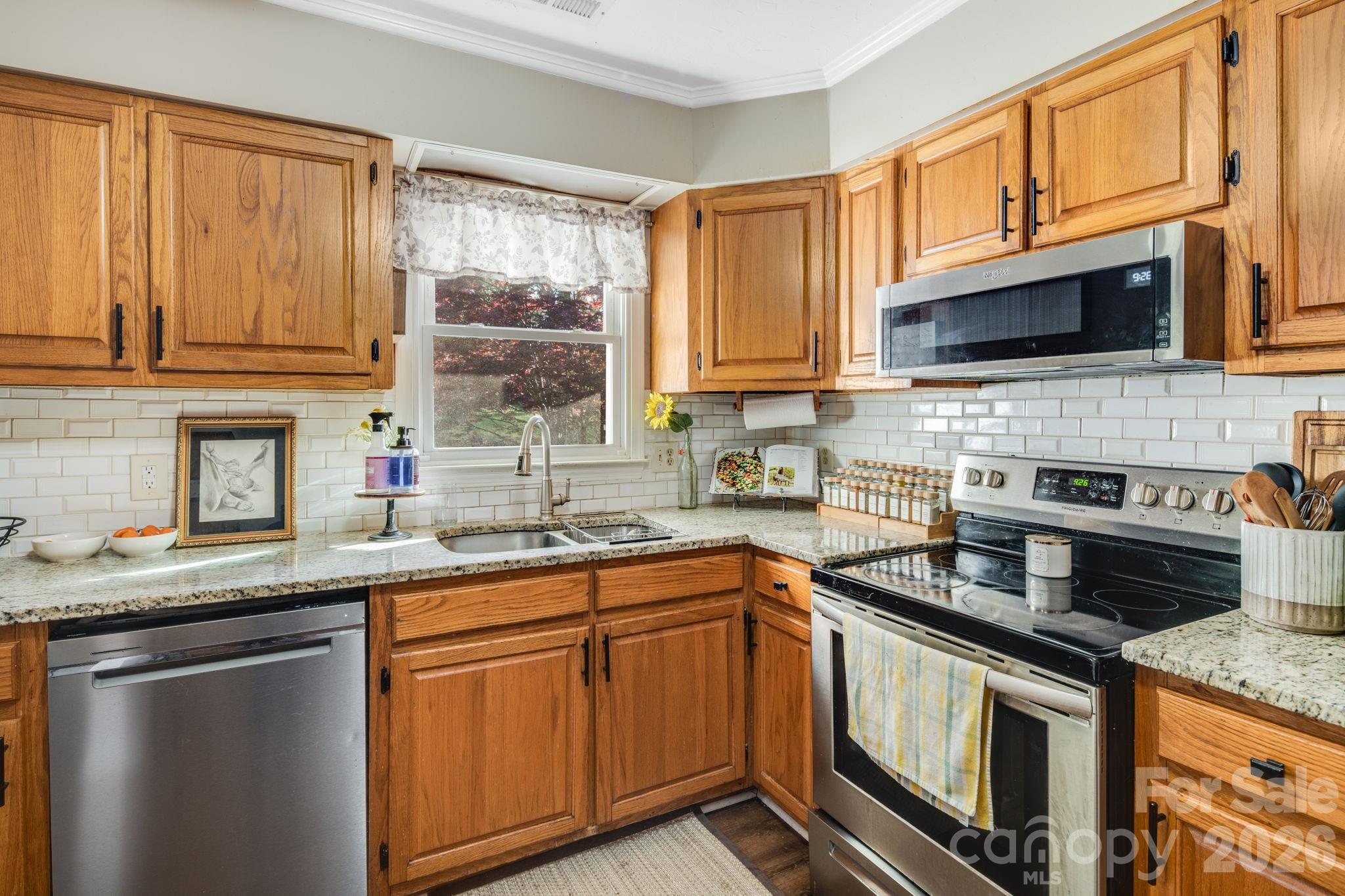 99 South Rowe Road Hendersonville, NC 28792 - Photo 11 of 40 a kitchen with stainless steel appliances granite countertop a sink stove and cabinets