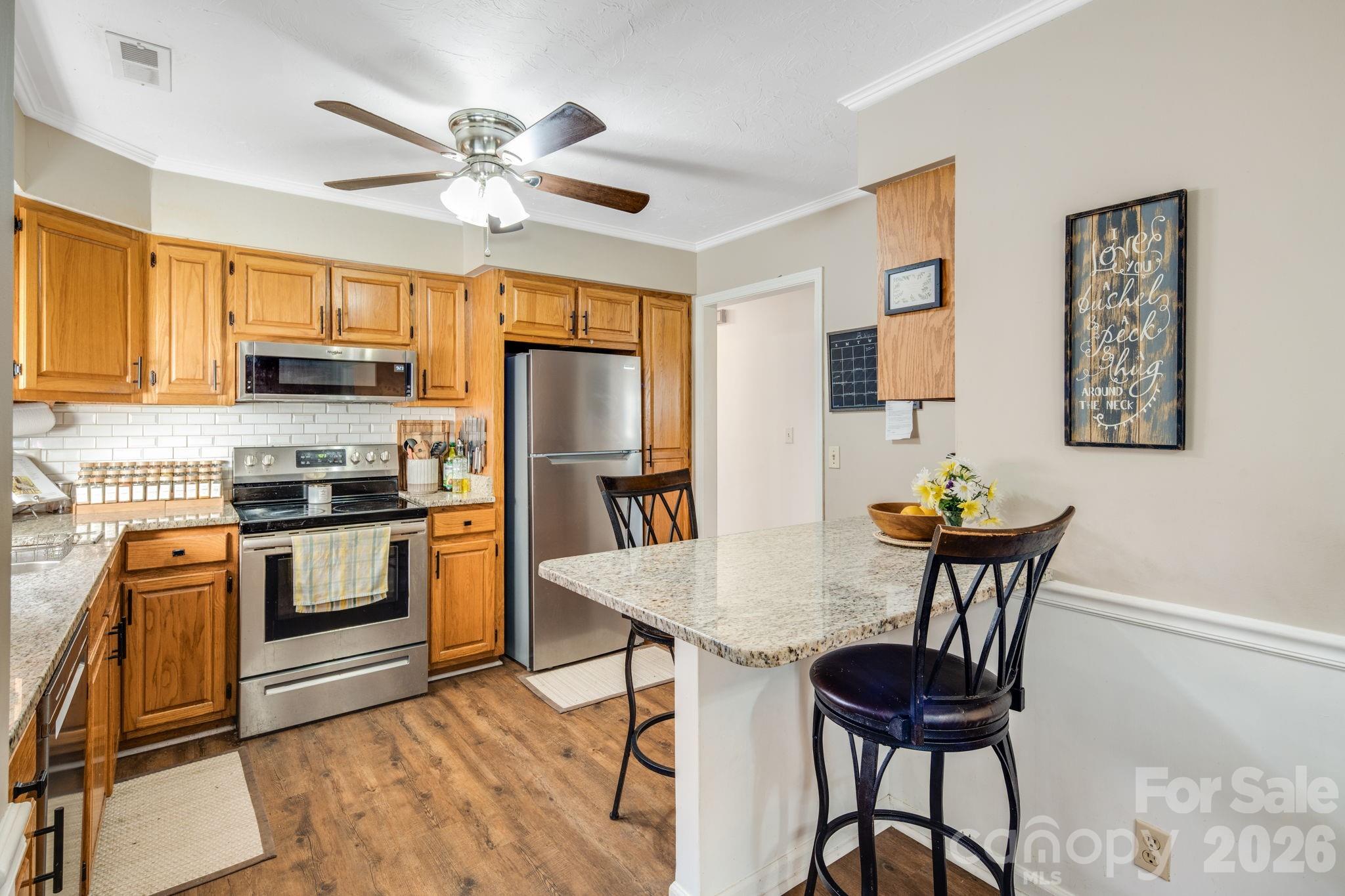 99 South Rowe Road Hendersonville, NC 28792 - Photo 9 of 40 a kitchen with stainless steel appliances granite countertop a stove top oven a refrigerator a sink with a dining table and chairs