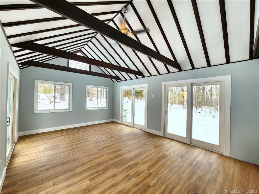 a view of an empty room with wooden floor and a window