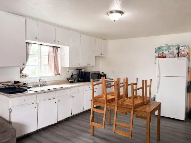 a kitchen with a table chairs white cabinets and white appliances