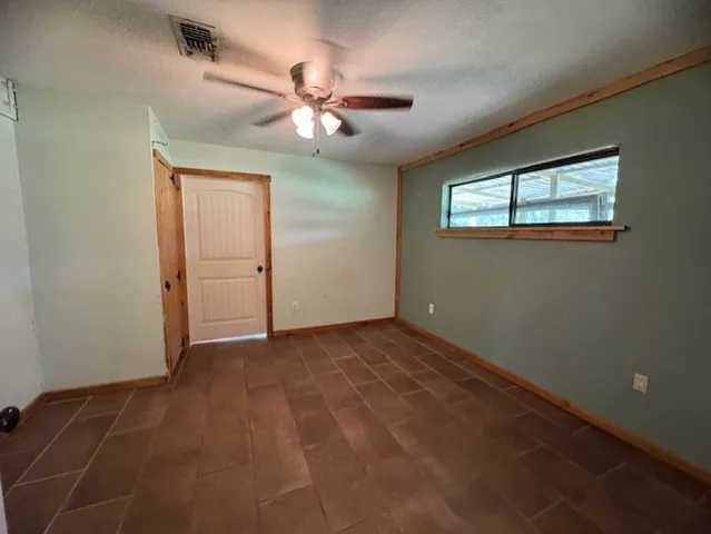 an empty room with windows and fan