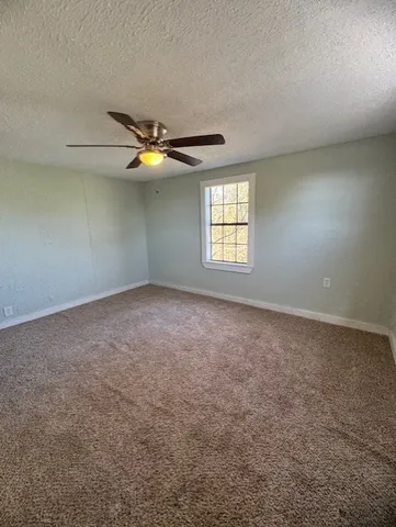 an empty room with windows and chandelier fan