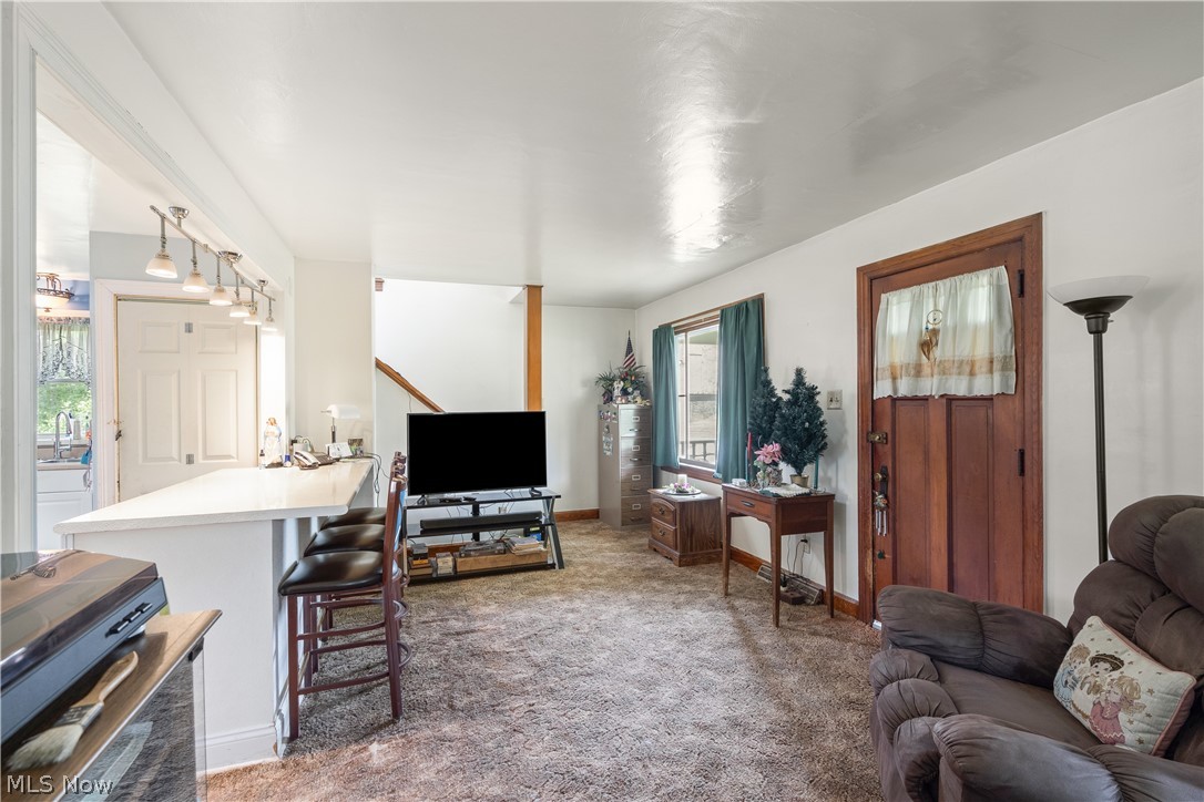 6324 Struthers Road Youngstown, OH 44514 - Photo 22 of 42 Open-concept living area featuring a breakfast bar with built-in track lighting, a wood-finish staircase, and a solid wood entry door