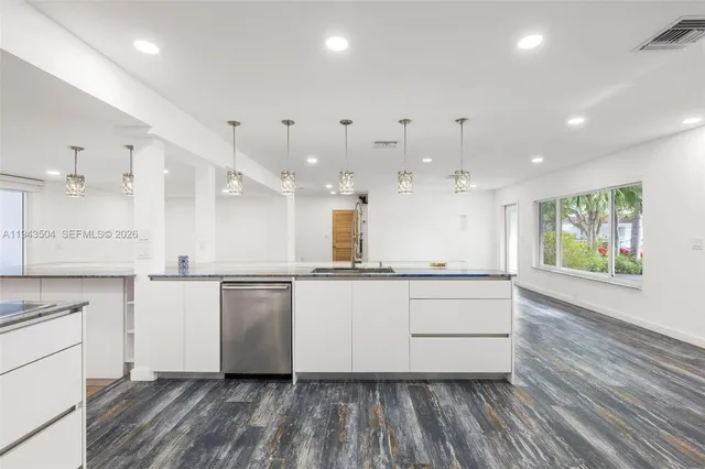 a kitchen with stainless steel appliances granite countertop a stove a sink and white cabinets with wooden floor