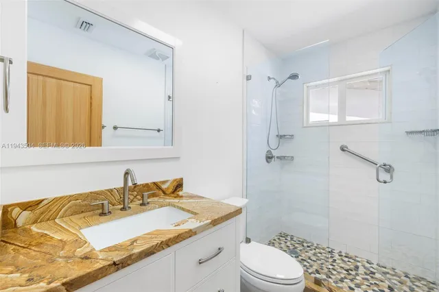 a bathroom with a granite countertop sink toilet and shower