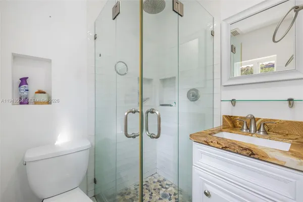 a bathroom with a granite countertop shower sink vanity and toilet