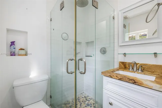 a bathroom with a granite countertop shower sink vanity and toilet
