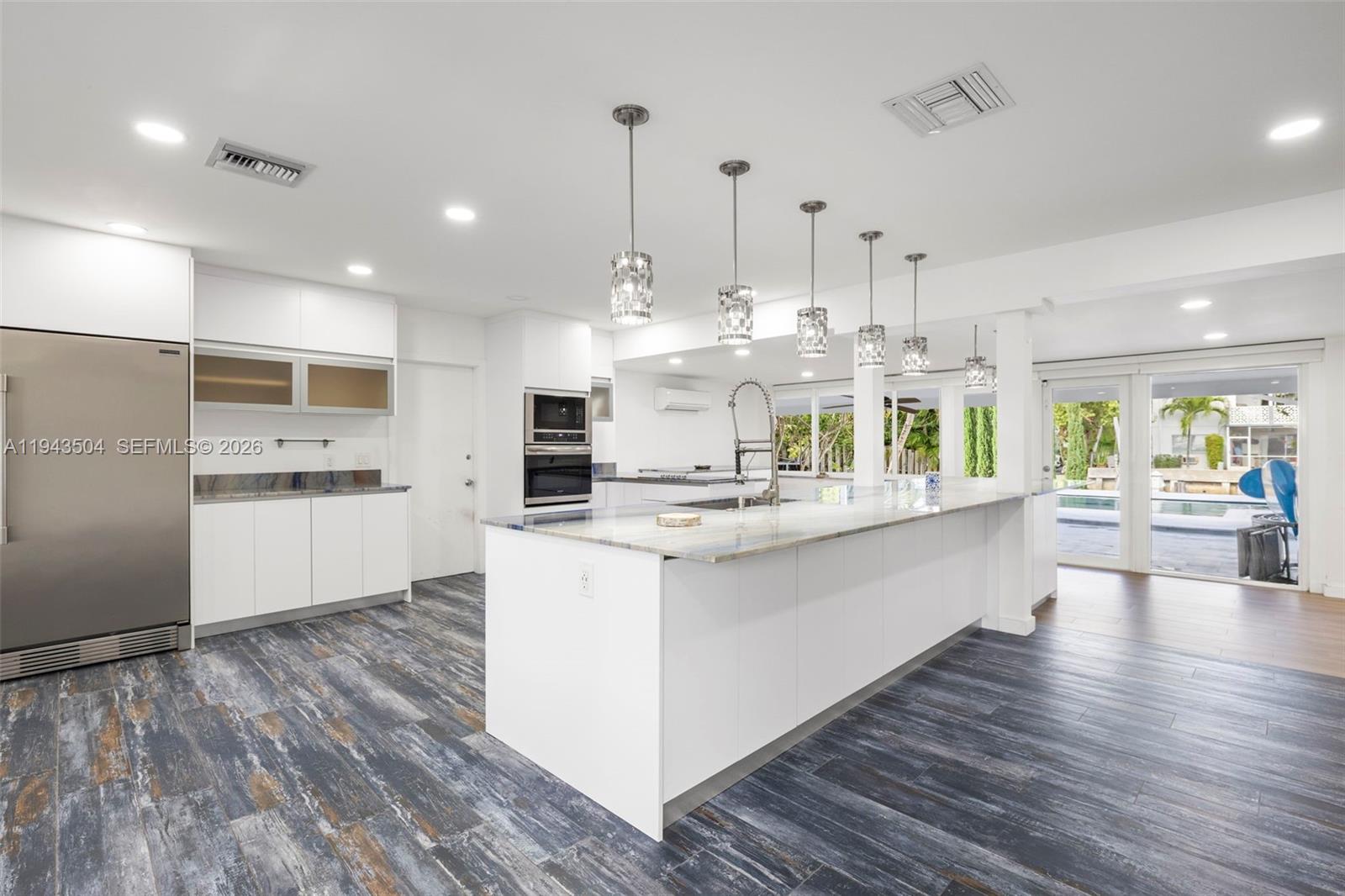 1895 Ixora Road North Miami, FL 33181 - Photo 10 of 42 a kitchen with stainless steel appliances kitchen island a white cabinets and wooden floor
