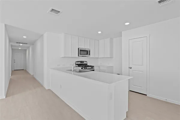 a kitchen with stainless steel appliances a refrigerator sink and white cabinets
