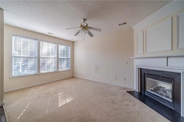 an empty room with a fireplace and a ceiling fan
