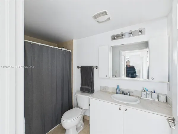 a bathroom with a granite countertop sink vanity mirror and toilet