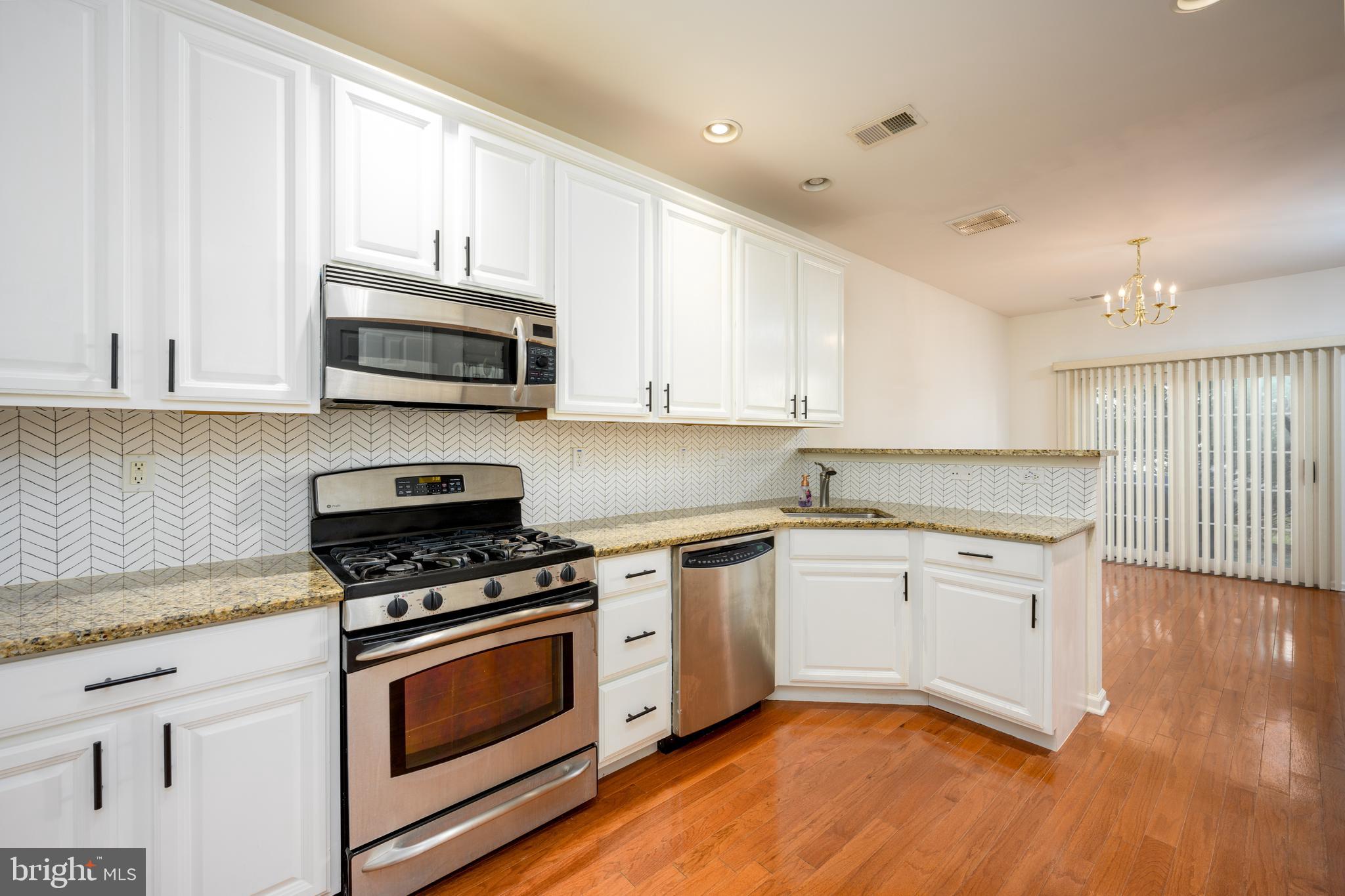 249 Concord Place Pennington, NJ 08534 - Photo 8 of 22 a kitchen with granite countertop a stove top oven a sink dishwasher and white cabinets with wooden floor
