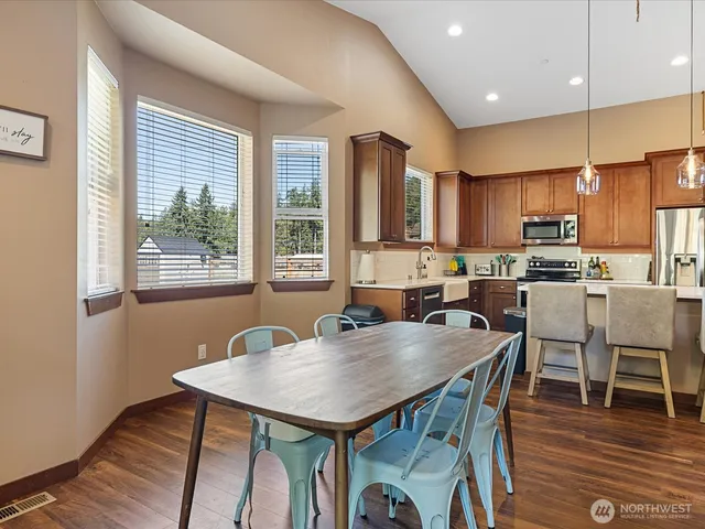 a kitchen with stainless steel appliances granite countertop a stove a refrigerator a kitchen island with a dining table and chairs