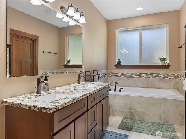 a bathroom with a granite countertop sink a large mirror and a bathtub