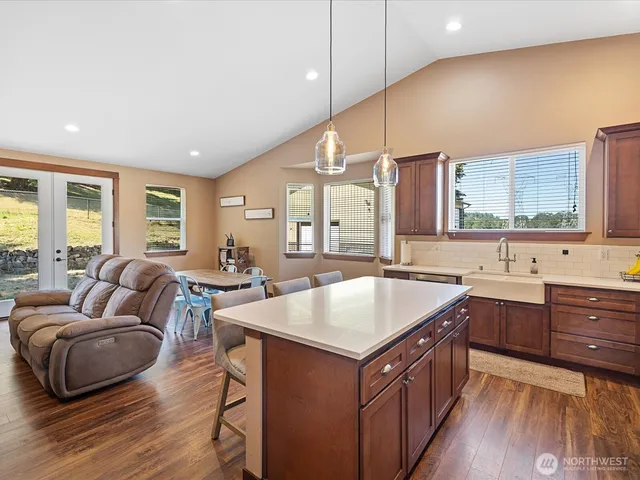 a living room with stainless steel appliances granite countertop a kitchen island a stove and a sink