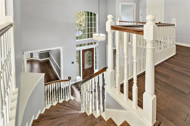 a view of staircase with lots of frames on wall and wooden floor