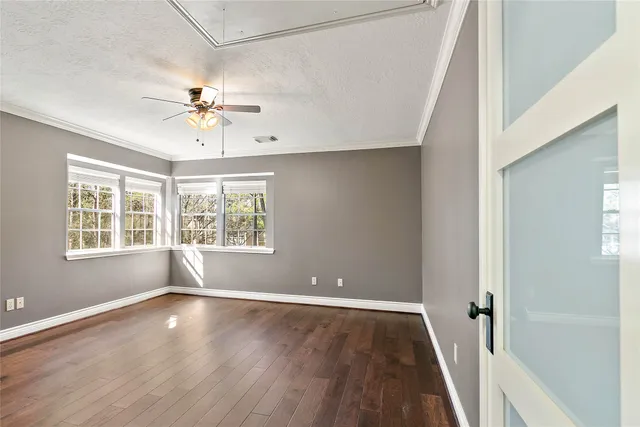 an empty room with wooden floor and windows