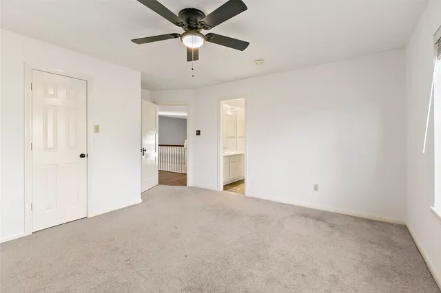 an empty room with chandelier fan and windows
