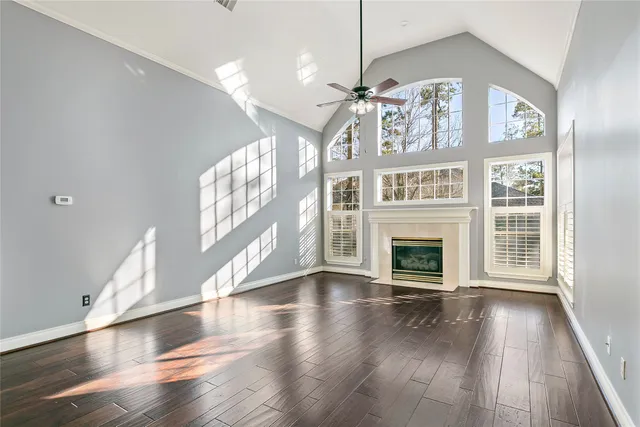 a view of an empty room with wooden floor fireplace and a window