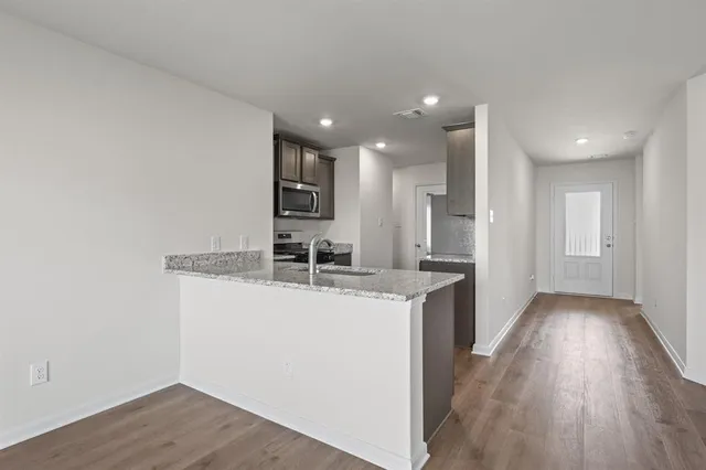a kitchen with stainless steel appliances granite countertop a sink stove and wooden floor