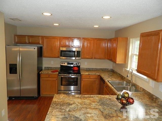 5822 Finestra Way Raleigh, NC 27610 - Photo 3 of 25 a kitchen with granite countertop a refrigerator stove and sink