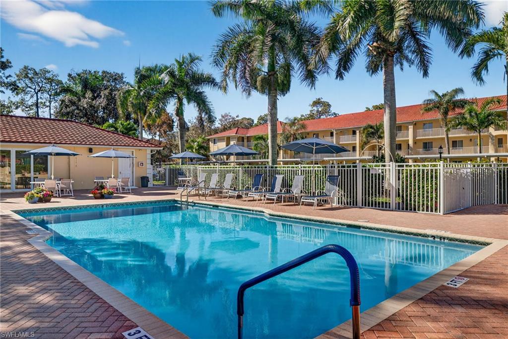 3665 Amberly Circle, Unit B101 Naples, FL 34112 - Photo 25 of 30 a view of a swimming pool with a table and chairs