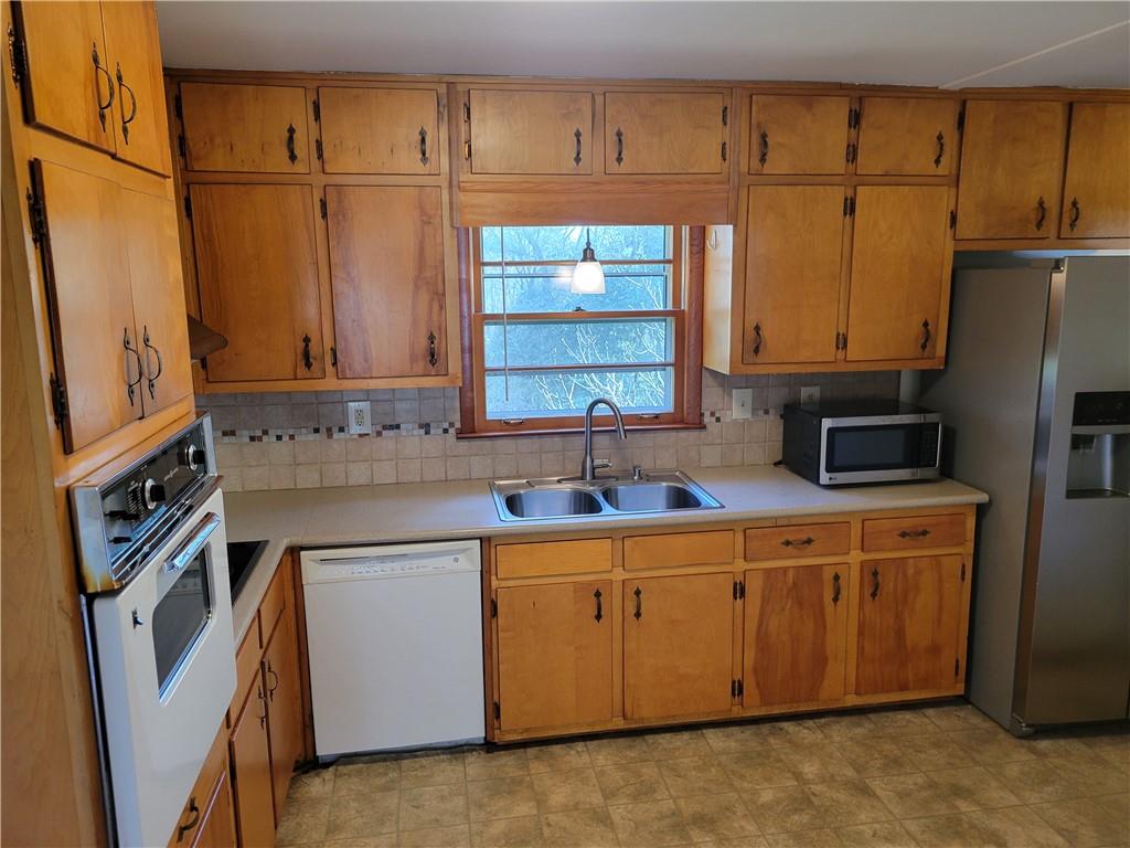 3009 Caldwell Road Northeast Brookhaven, GA 30319 - Photo 5 of 22 a kitchen with stainless steel appliances granite countertop a sink a stove a refrigerator a washer dryer and white cabinets