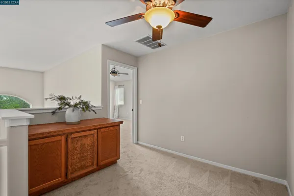 a room with a chandelier fan and kitchen view