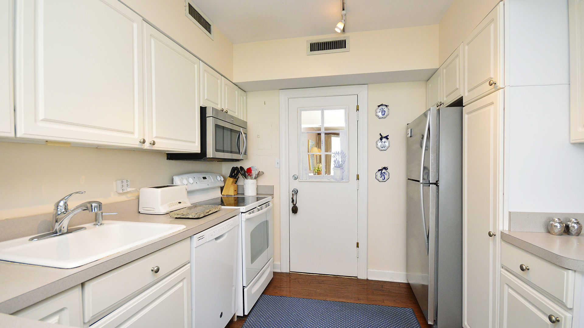 1616 Sheridan Road, Unit 7A Wilmette, IL 60091 - Photo 11 of 22 a kitchen with a sink dishwasher and white cabinets with wooden floor