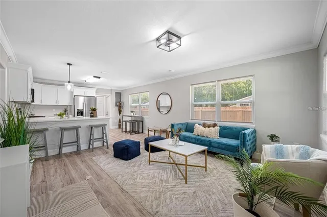 a living room with furniture a rug kitchen view and a window