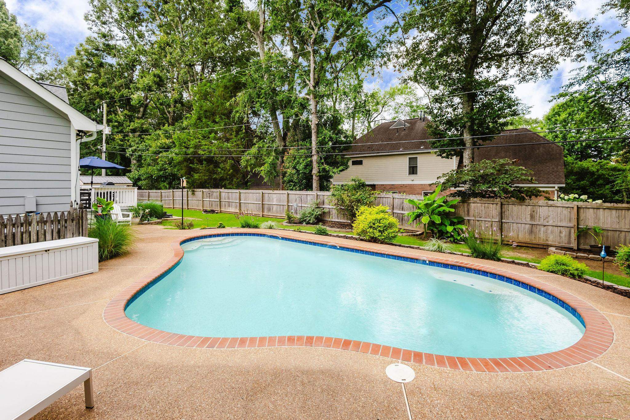 305 Great Falls Road Collierville, TN 38017 - Photo 18 of 23 Freeform swimming pool with integrated steps, brick coping, and a surrounding aggregate concrete deck
