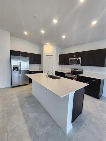 a large kitchen with a large counter top a sink a stove and a microwave oven