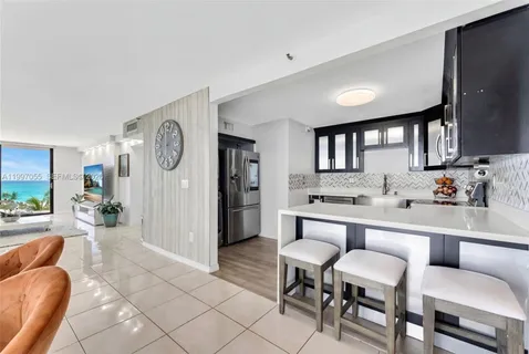 a large living room with stainless steel appliances furniture a rug and a window