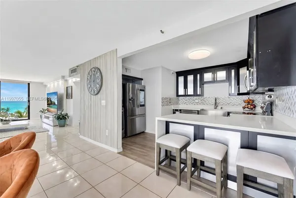 a large living room with stainless steel appliances furniture a rug and a window