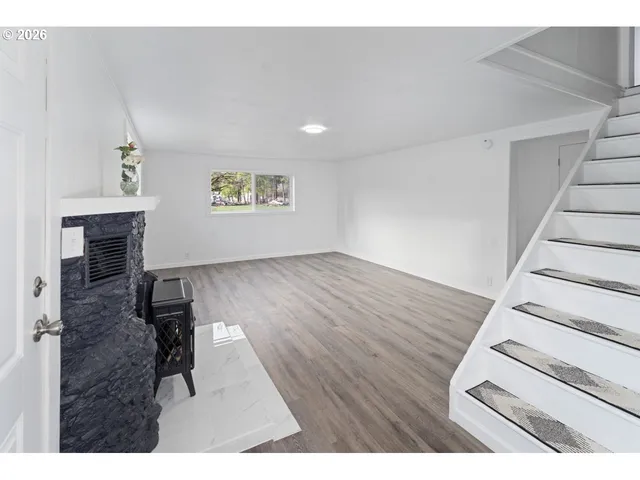 a view of empty room with wooden floor and fireplace