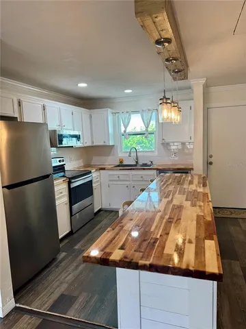 a kitchen with kitchen island a counter top space a sink stainless steel appliances and cabinets
