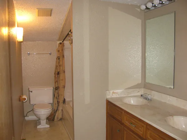 a bathroom with a granite countertop sink toilet and shower
